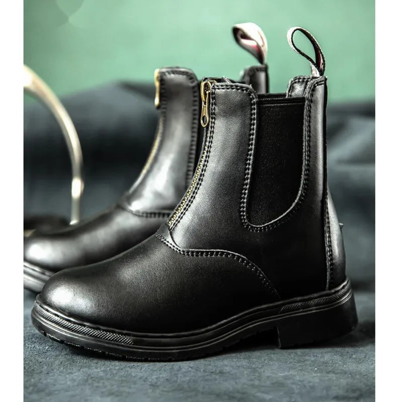 Black leather boot with a zipper on a gray surface . Ghoddosh