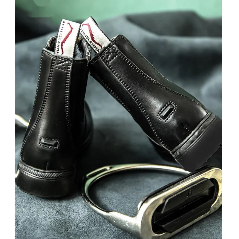 Black leather boot with a zipper on a gray surface . Ghoddosh